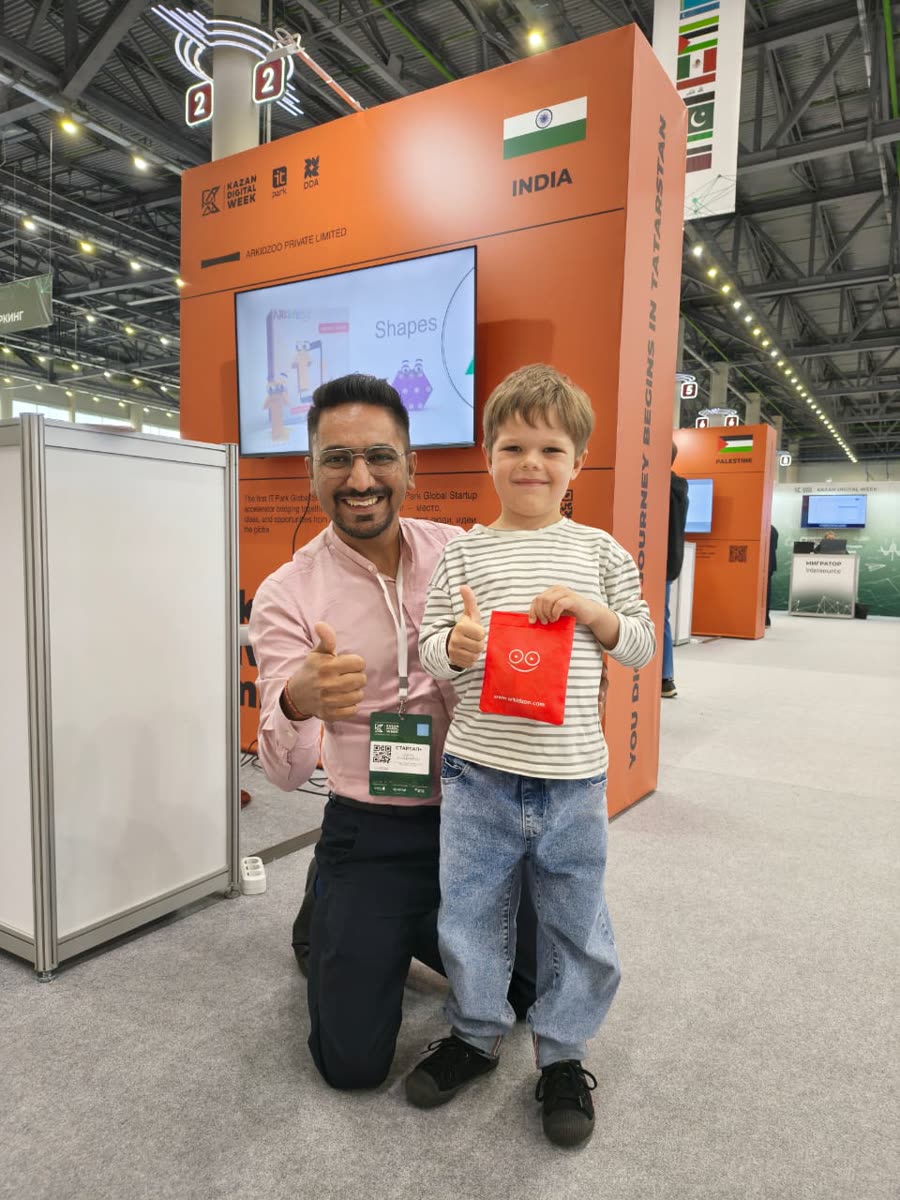 ARKidzoo's founder and a young visitor giving a thumbs-up with ARKidzoo merchandise at the Kazan Digital Week booth