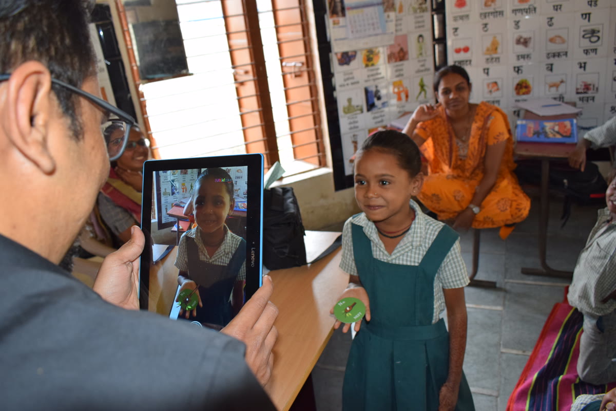 A schoolgirl smiling at her own AR moment on a tablet in a rural classroom